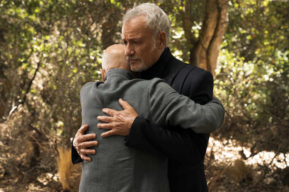 Q reacts uncertainly to a warm hug from Jean-Luc Picard.
