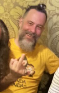 An almost-49-year-old in a bright orange t-shirt flipping the bird to the camera with a big grin on her face.