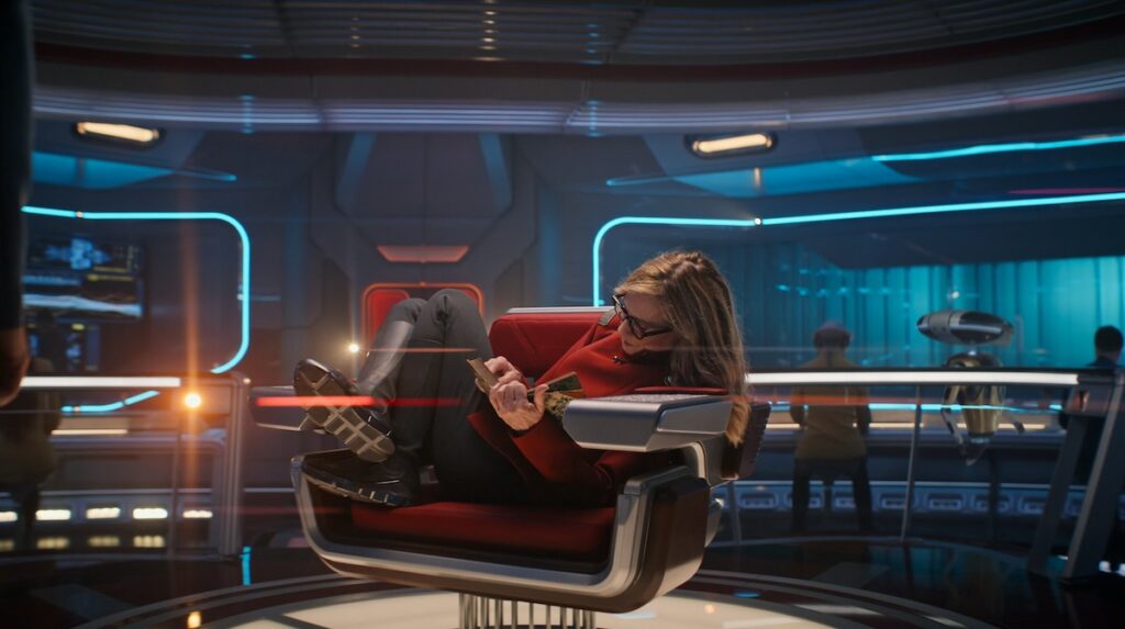 A Starfleet captain curls up in her captain's chair as though it's a porch swing, having not even bothered to take her boots off.