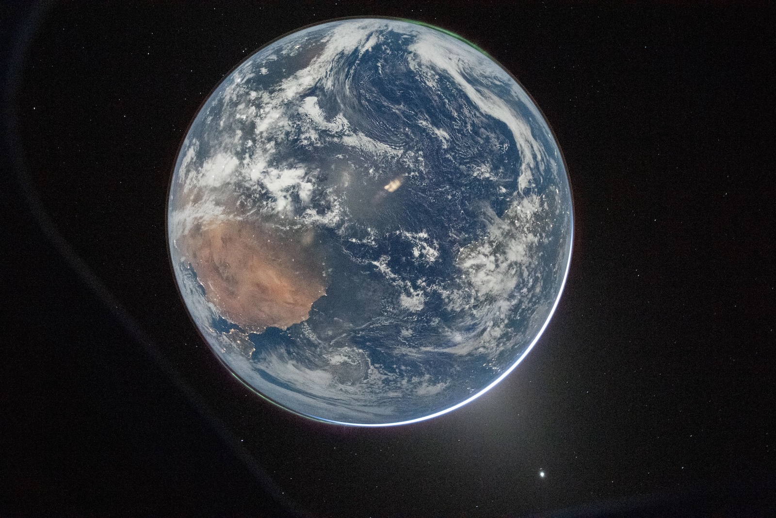 The Earth hangs in space, a beautiful blue ball. Photo taken from a good distance away, aboard the Artemis II spacecraft.