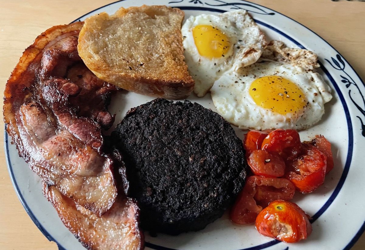 A "full English" breakfast, bacon, blood pudding, tomatoes, fried bread, and two eggs over easy